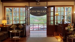 A cozy interior with a sofa, a small table, and a lamp. A sign reading "CASA VALLEJO" is visible.