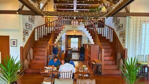 A spacious hotel lobby with a grand staircase, wooden furniture, and a warm ambiance.