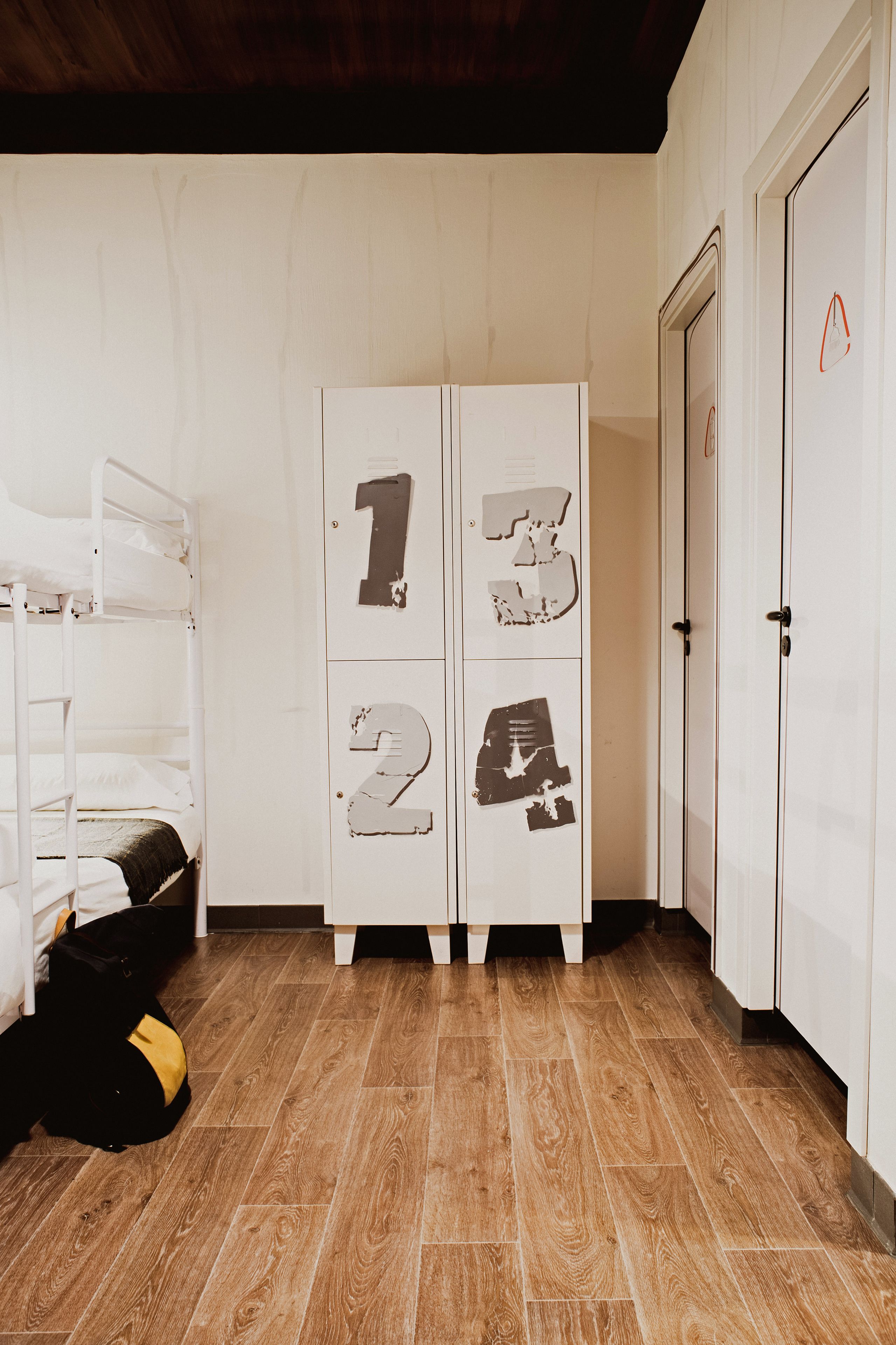 A room with bunk beds, a wardrobe with numbered compartments, and a door with a red object on it.