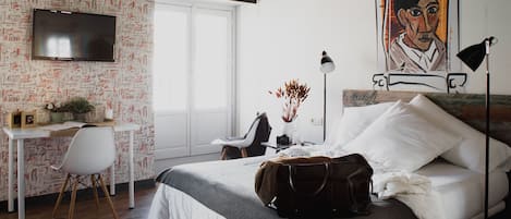 Ein Schlafzimmer mit einem Bett, einem Schreibtisch, einem Stuhl, einem Fernseher und einem Bild an der Wand.