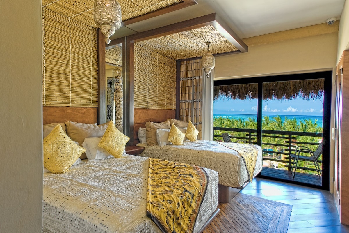 Ein Schlafzimmer mit zwei Betten, einem großen Fenster und Blick aufs Meer.