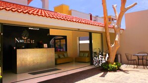 A hotel reception with a modern design, featuring a reception desk, seating area, and a unique tree sculpture.
