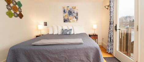 A bedroom with a large bed, a window with a view, and a wall with decorative items.