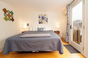 A bedroom with a large bed, a window with a view, and a wall with decorative items. - The Whitetail and Suites (Lincoln)