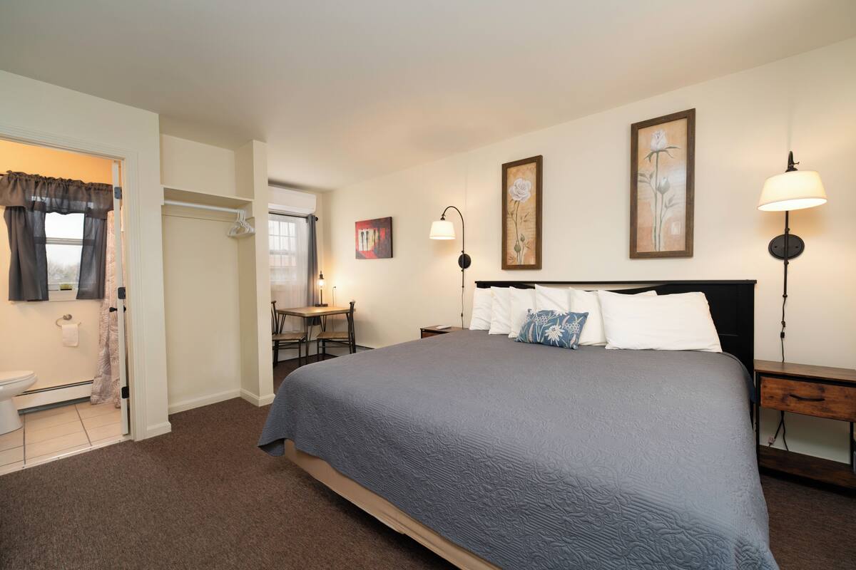 A bedroom with a bed, bedside tables, a desk, and a chair.