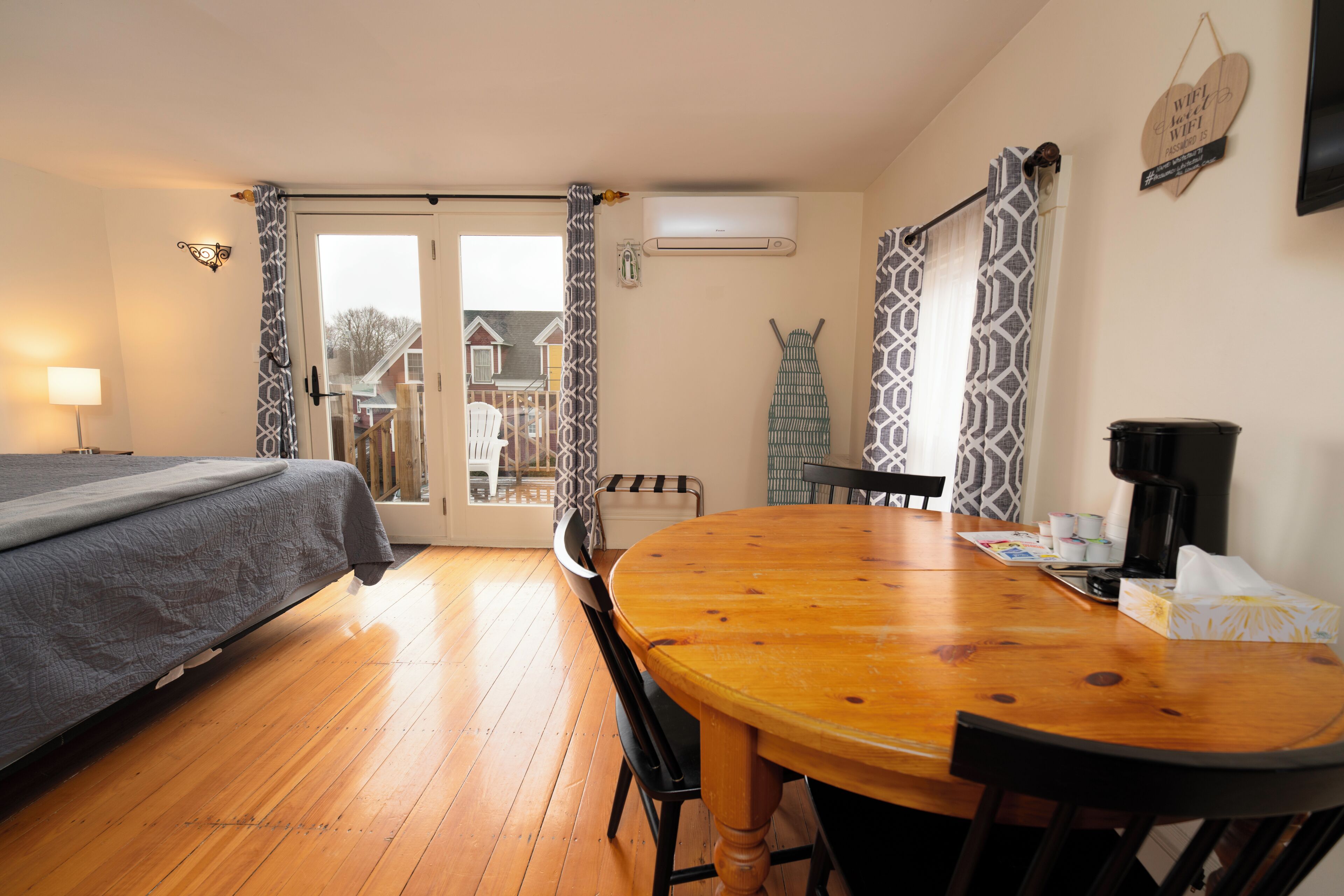 Una habitación con cama, una mesa de comedor, sillas, una cafetera y vistas a través de una puerta.