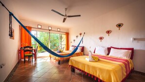 A room with two beds, a hammock, a desk, and a view of greenery outside. - Casa Don Diego (Tulum)
