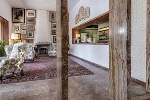 A lobby with a fireplace, framed pictures on the wall, and a reception desk. - Augustus Hotel & Resort (Forte dei Marmi)