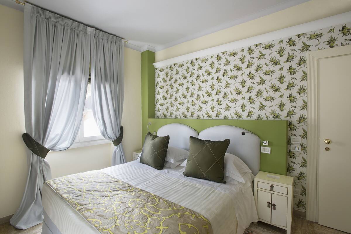 Une chambre à coucher avec un lit, des rideaux, une table de chevet et une porte.