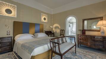 A hotel room with a large bed, a wooden chair, a dresser, and a mirror.