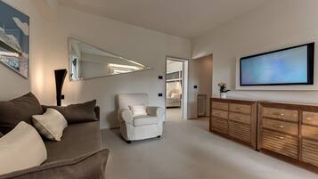 Ein modernes Wohnzimmer mit einer Couch, einem Sessel und einem großen Fernseher auf einer Holzkommode.
