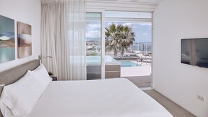 Habitación de hotel con cama, televisión, balcón con piscina y vista a la ciudad.