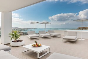 Terraza en la azotea con mobiliario blanco, una planta en maceta y un cuenco de frutas.