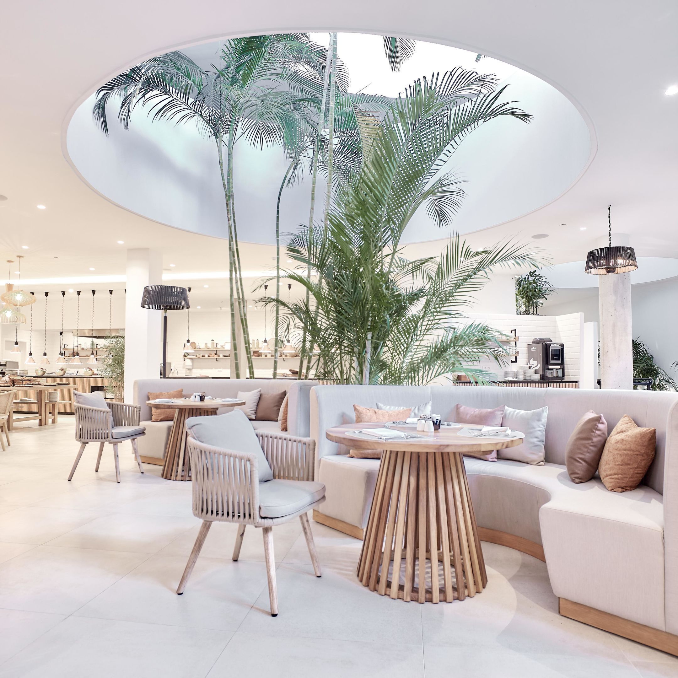 Un interior moderno con una zona de estar central, un comedor y una cocina al fondo.