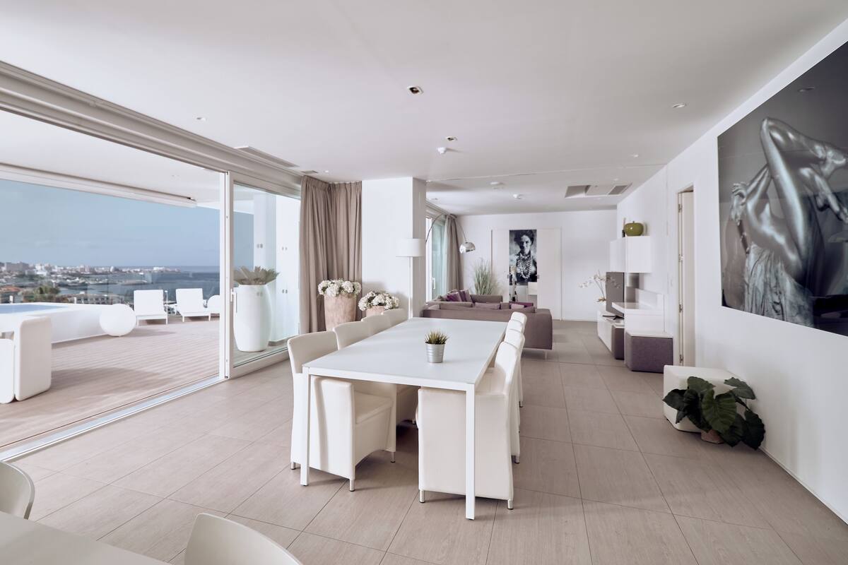 A modern living room with a large dining table, sofas, and a view of the city.
