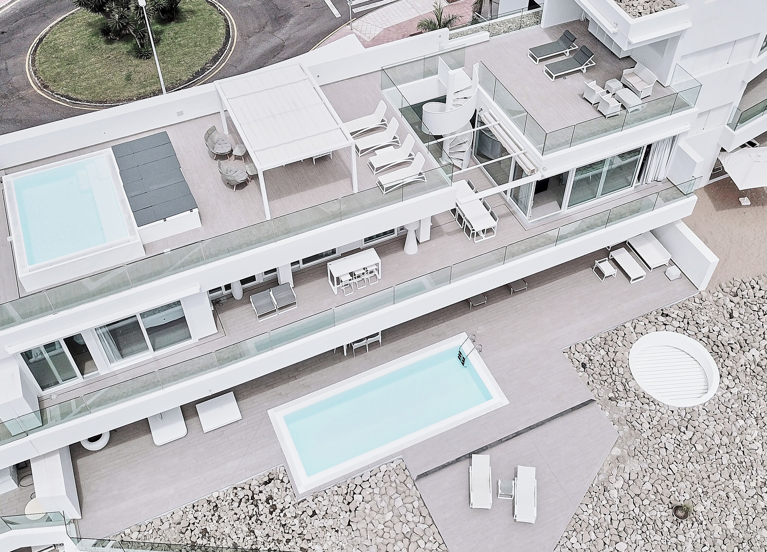 A modern hotel with a rooftop pool, outdoor seating areas, and a spacious balcony.