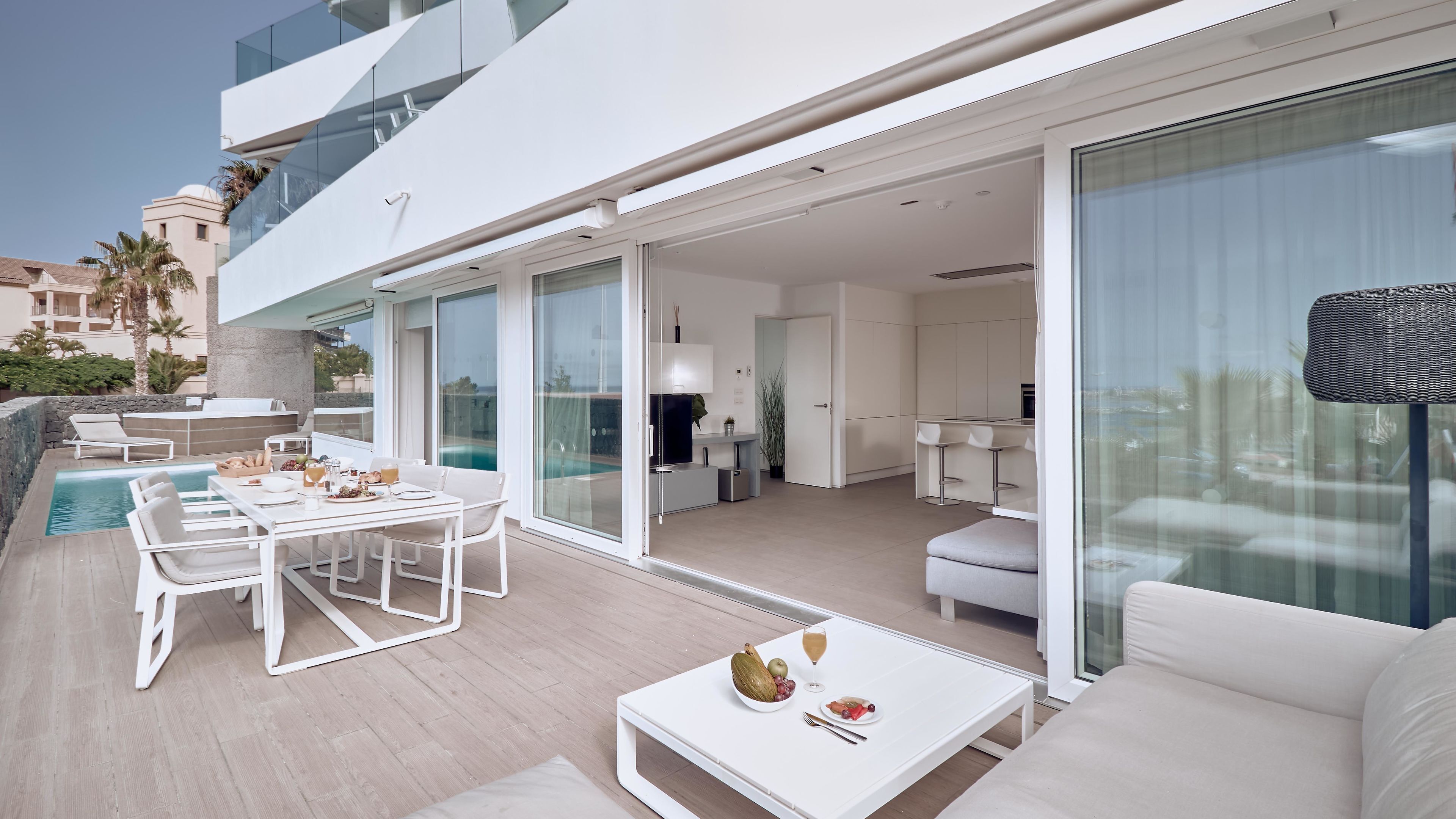 A modern outdoor living area with a pool, dining table, and seating.