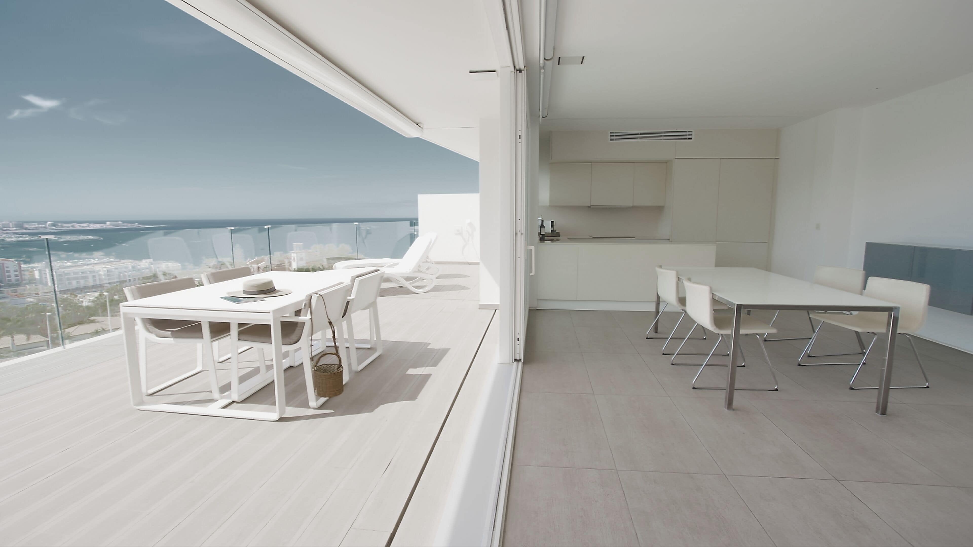 Een moderne, open woonruimte met balkon en uitzicht op een stadsgezicht.