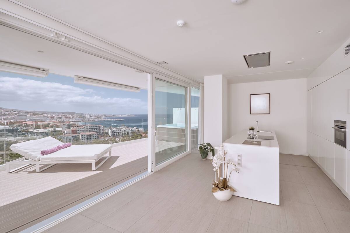 A modern apartment with a balcony, a kitchen, and a view of the city.