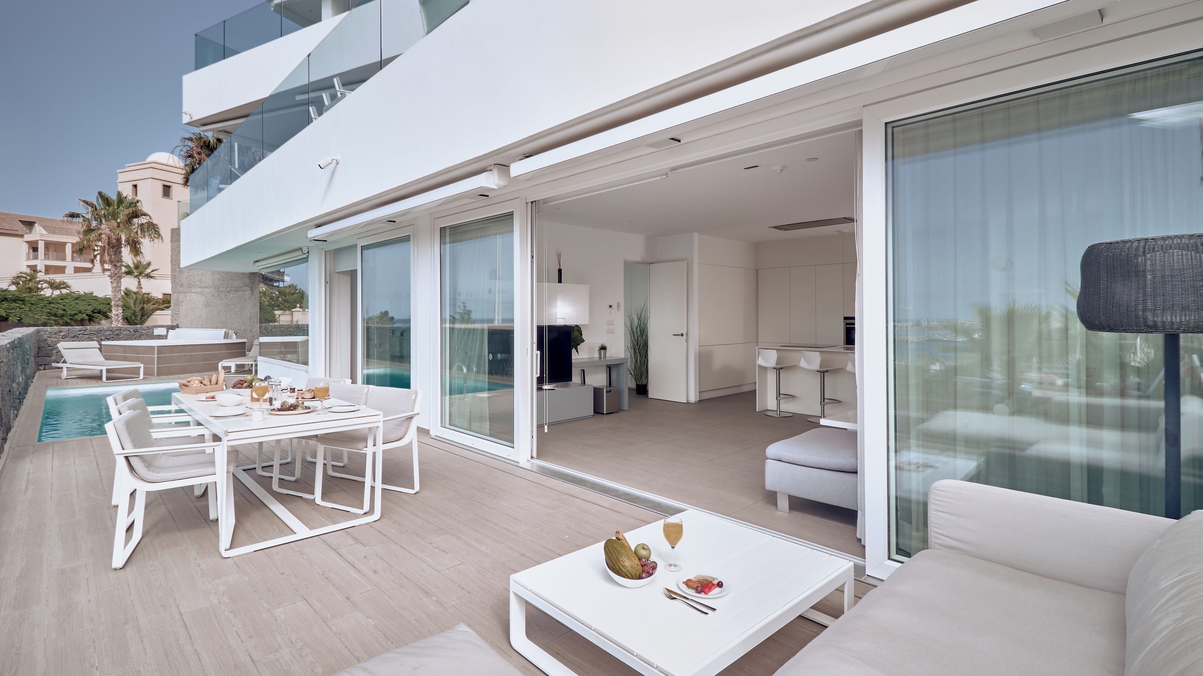 Una zona esterna moderna con piscina, tavolo da pranzo e posti a sedere.