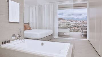 Un dormitorio moderno con una cama grande, una bañera y un balcón con vista a la ciudad.