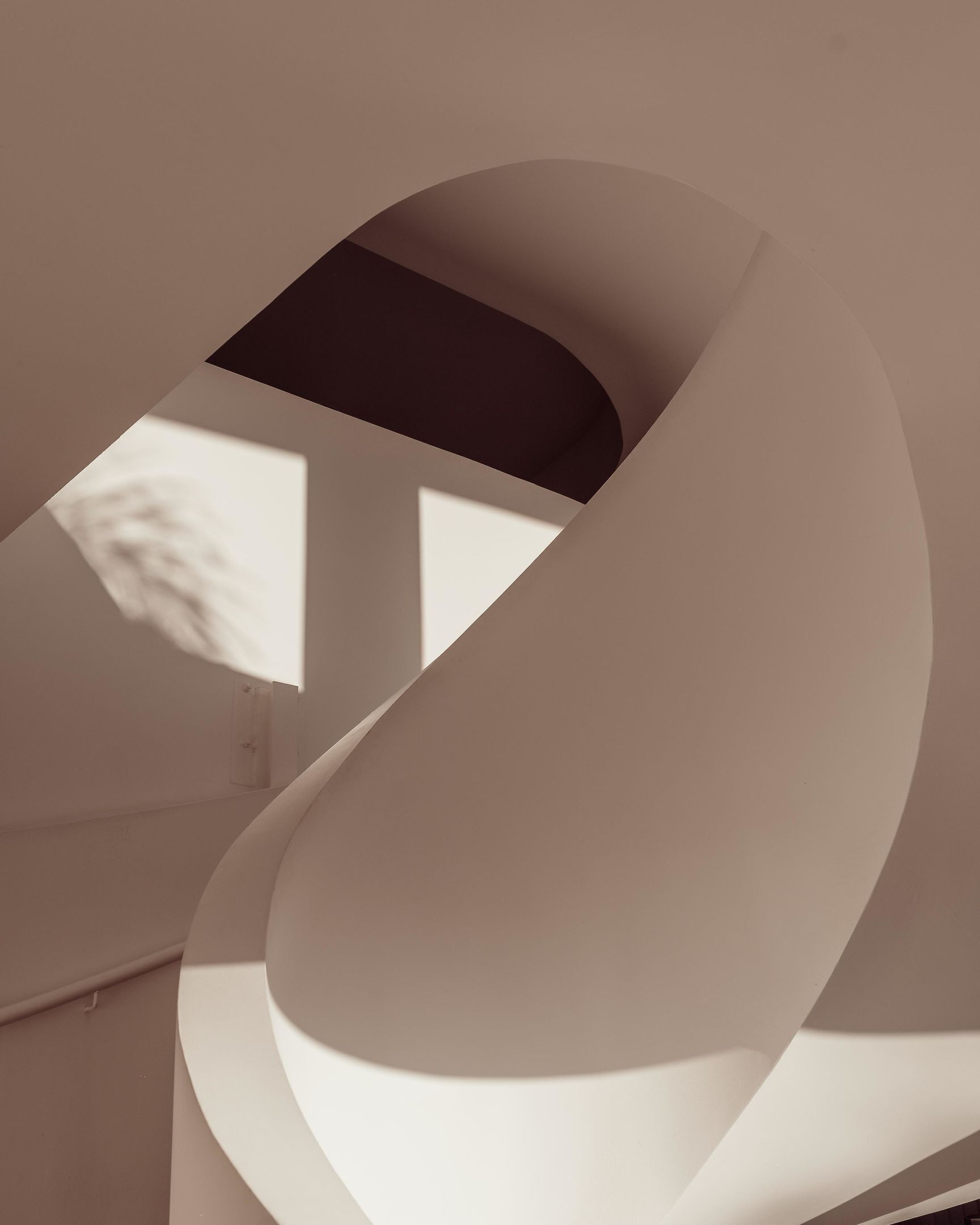 Ein modernes Interieur mit geschwungenen architektonischen Elementen und einem Fenster, das einen Schatten wirft.