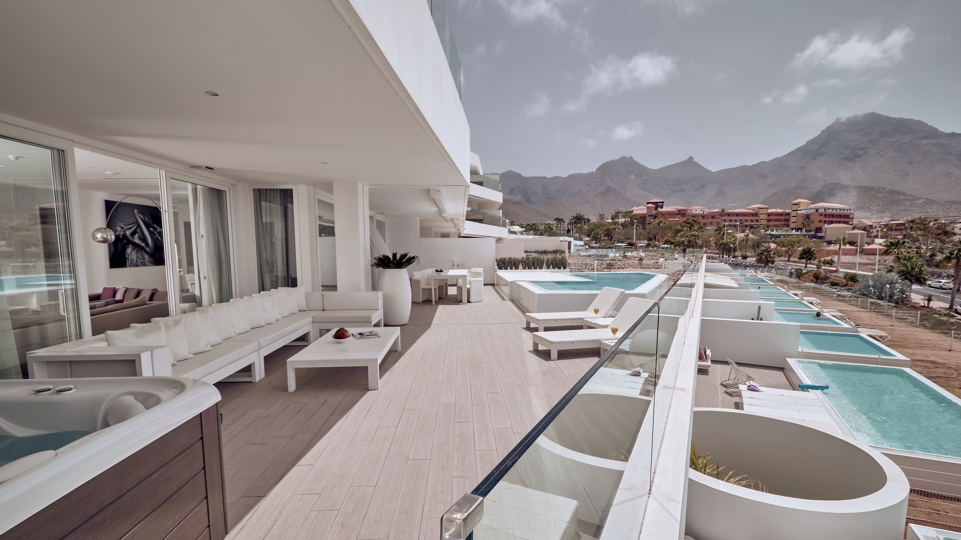 Un espace de détente extérieur moderne, doté d’une piscine, de sièges et offrant une vue sur les montagnes.