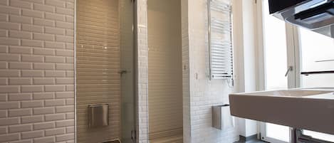 Ein modernes Badezimmer mit einer Duschkabine, einem weißen Waschbecken und einem Handtuch auf dem Boden.