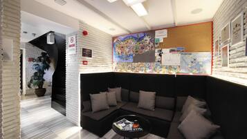 Un área de descanso moderna con un sofá seccional negro, una mesa redonda de centro y un gran mapa mural.