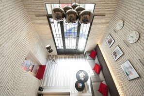 A modern interior with a brick wall, a sofa with red cushions, a coffee table, and a wall clock.