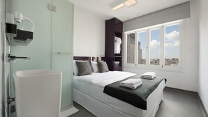 A modern hotel room with a bed, a bathroom with a sink, and a window with a city view. - The Central House Istanbul Taksim (Istanbul)