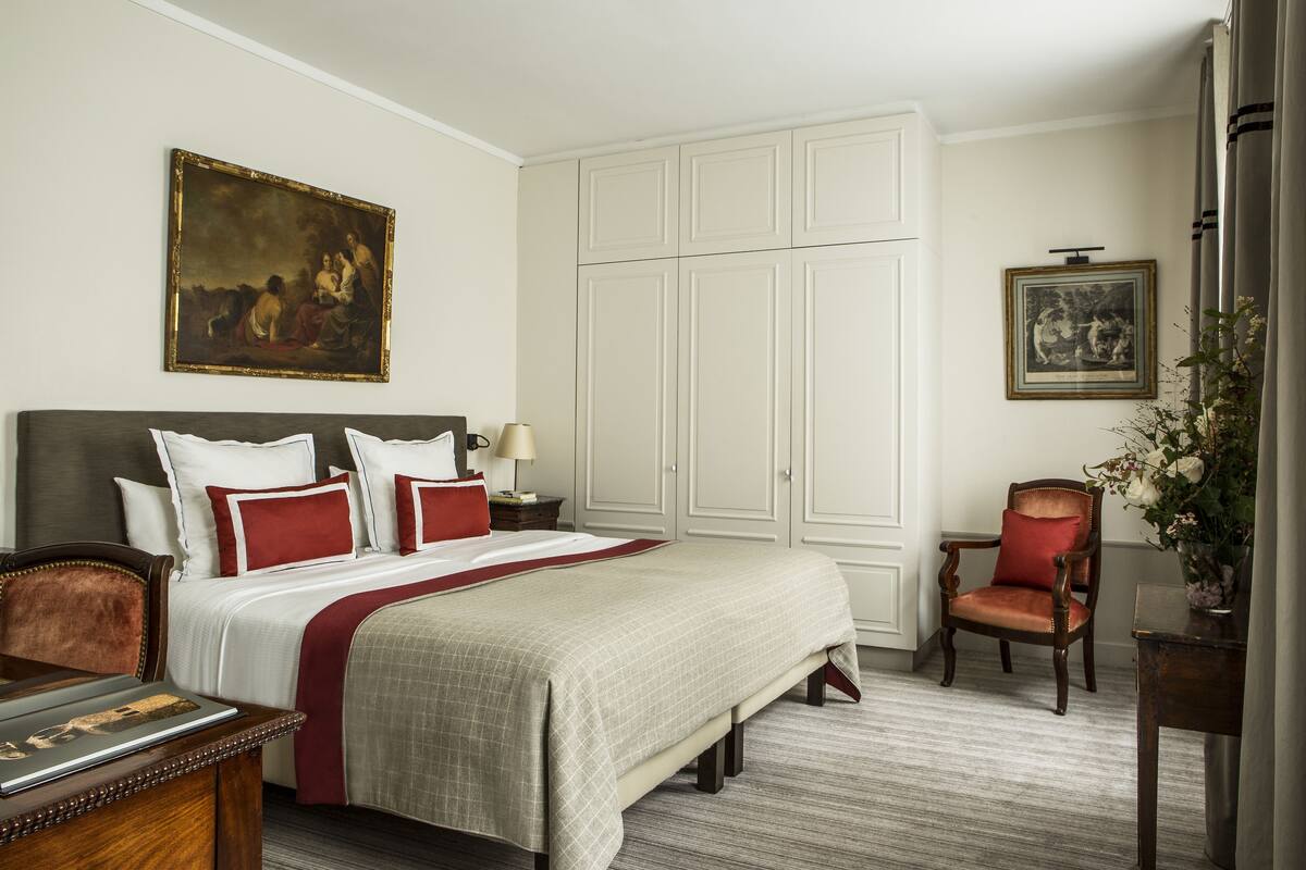 A hotel room with a large bed, a desk, a chair, and a wardrobe.