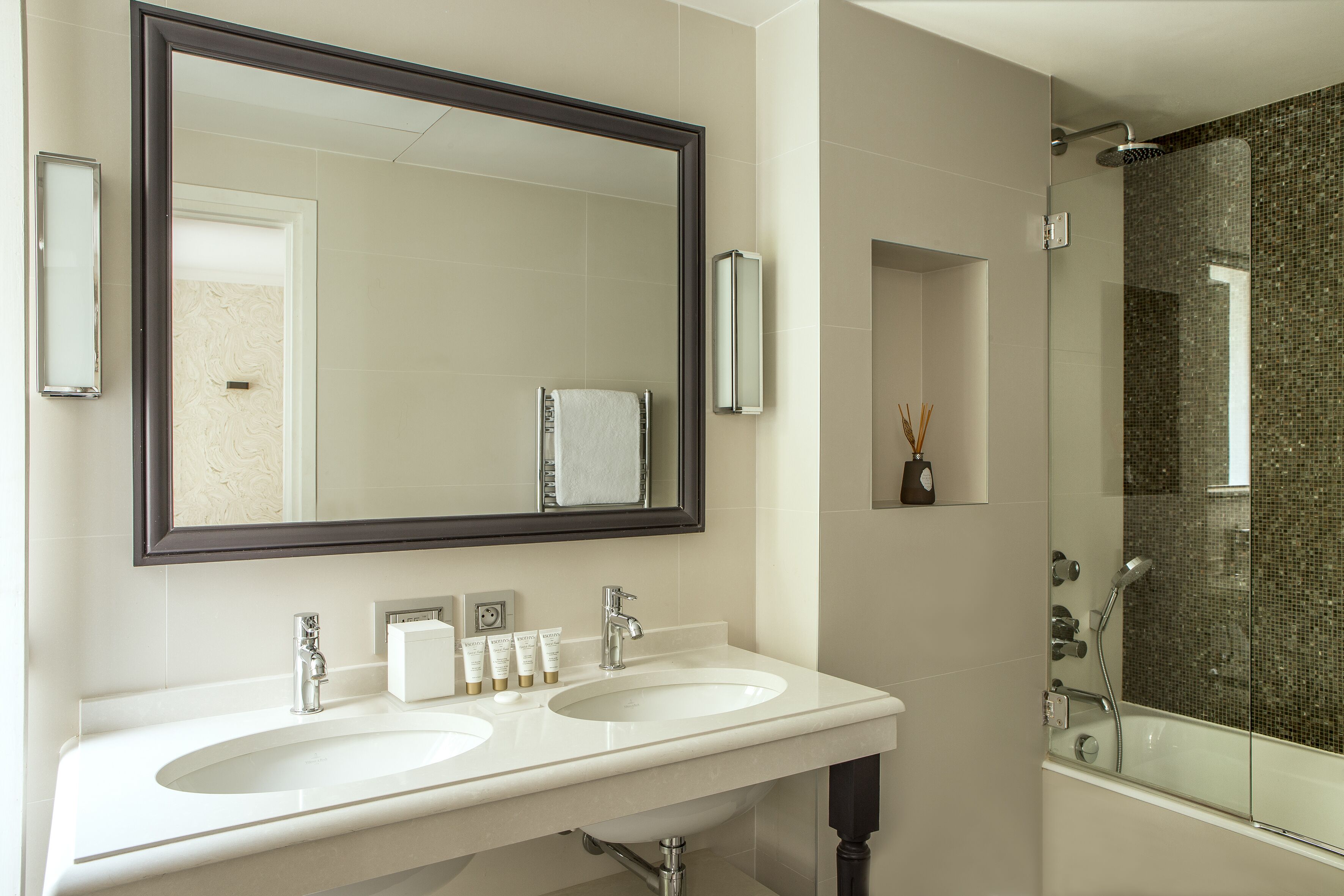 A bathroom with two sinks, a large mirror, and a shower area.