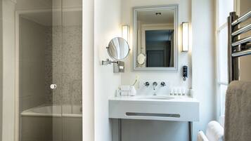A modern bathroom with a glass-enclosed shower, a white sink with a mirror, and a towel rack.