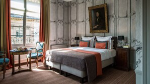 A hotel room with a bed, a chair, a table, and a nightstand.
