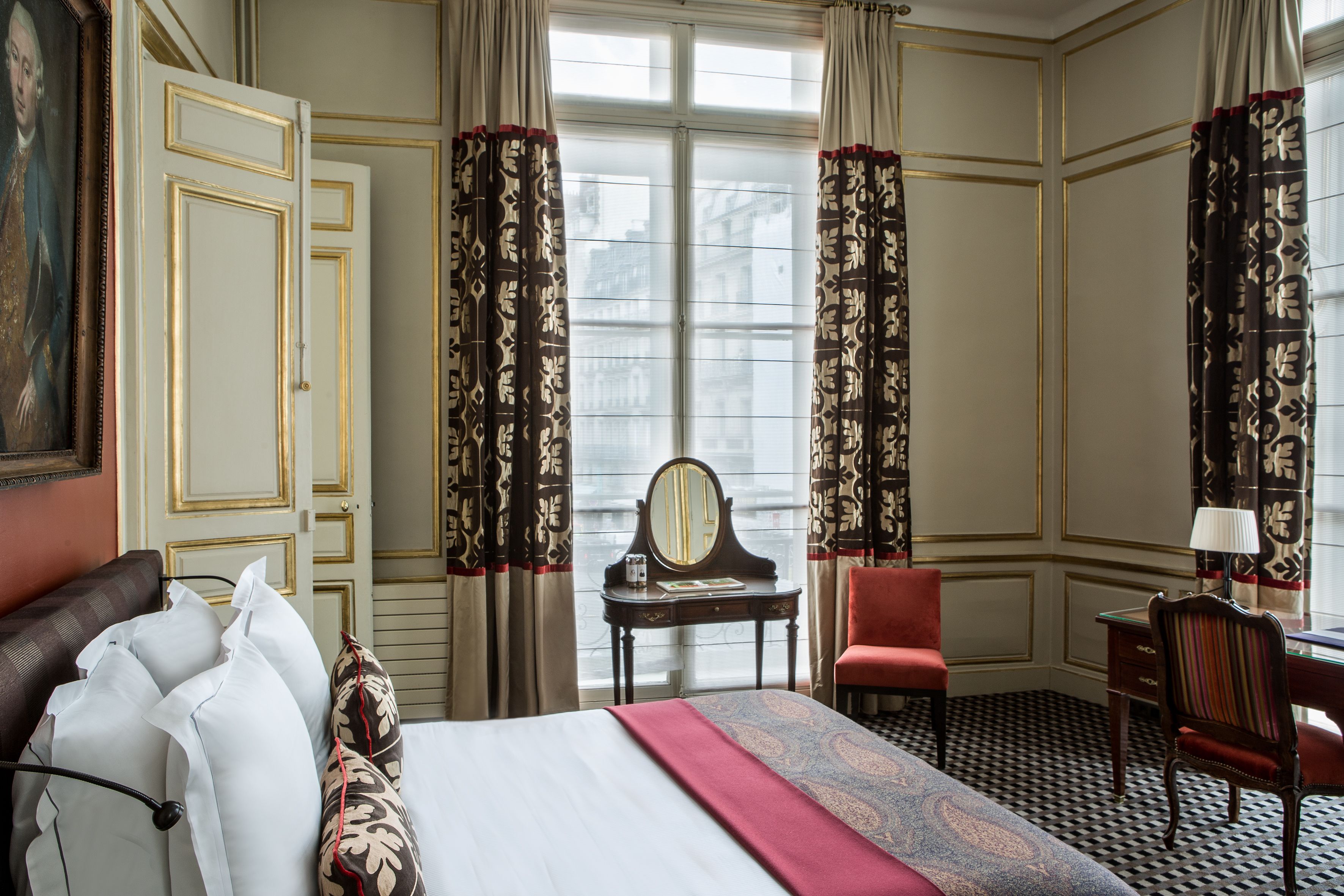 Habitación de hotel con cama, escritorio, silla y ventana con cortinas.