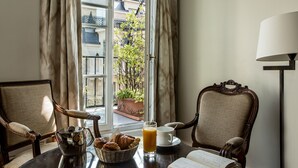 A breakfast setting with a table, chairs, a basket of croissants, a glass of orange juice, and an open menu.