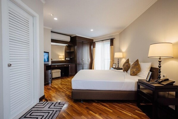 Une chambre d’hôtel avec un grand lit, des lampes de chevet, un bureau avec une chaise, une armoire et un téléviseur.