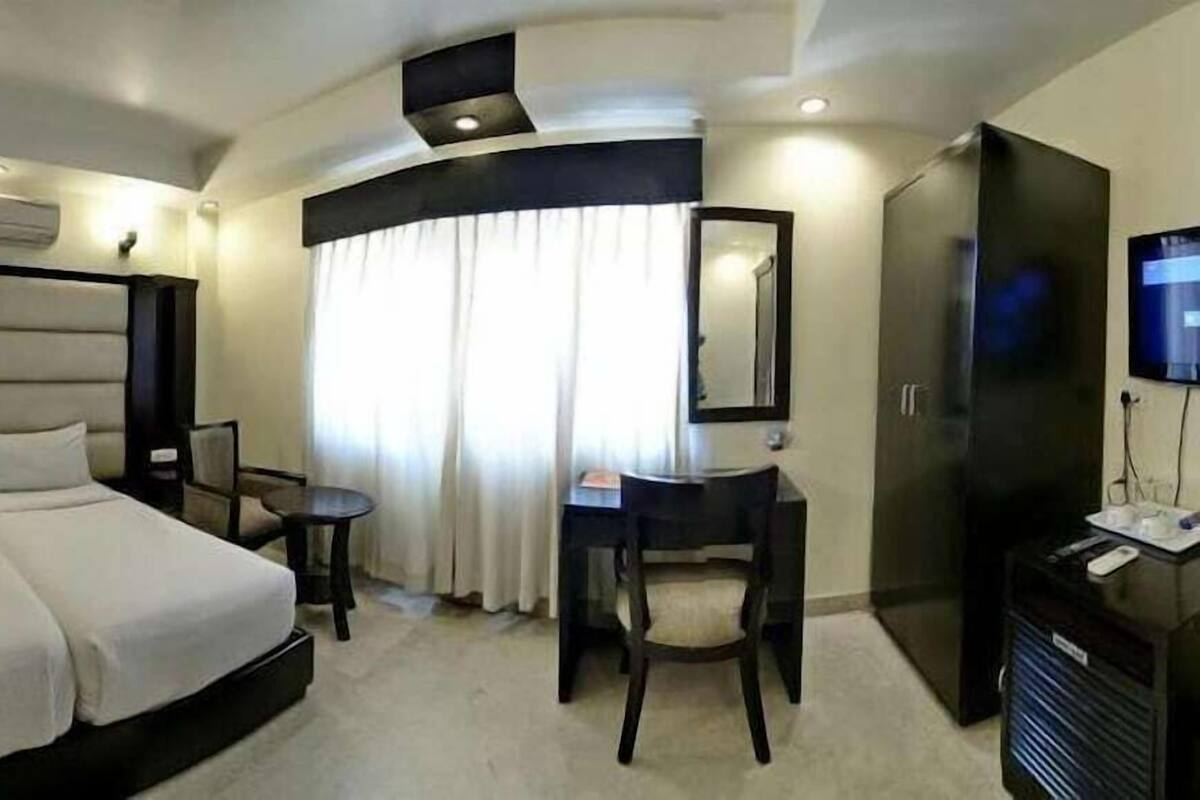 Une chambre d’hôtel avec un lit double, un bureau, une chaise, une télévision et une armoire.