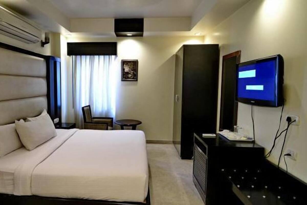 Une chambre d’hôtel avec un grand lit, un téléviseur à écran plat, un bureau et une chaise.