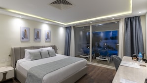 Una habitación de hotel moderna con una cama grande, un escritorio y vistas a una piscina.