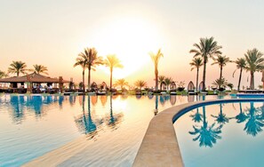 A resort pool with palm trees and a gazebo.