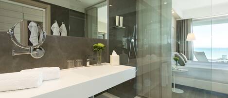 A modern bathroom with a large mirror, white countertop, and a glass-enclosed shower area.