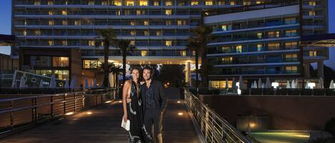 A multi-story hotel with a modern design, featuring a covered walkway and outdoor seating area.