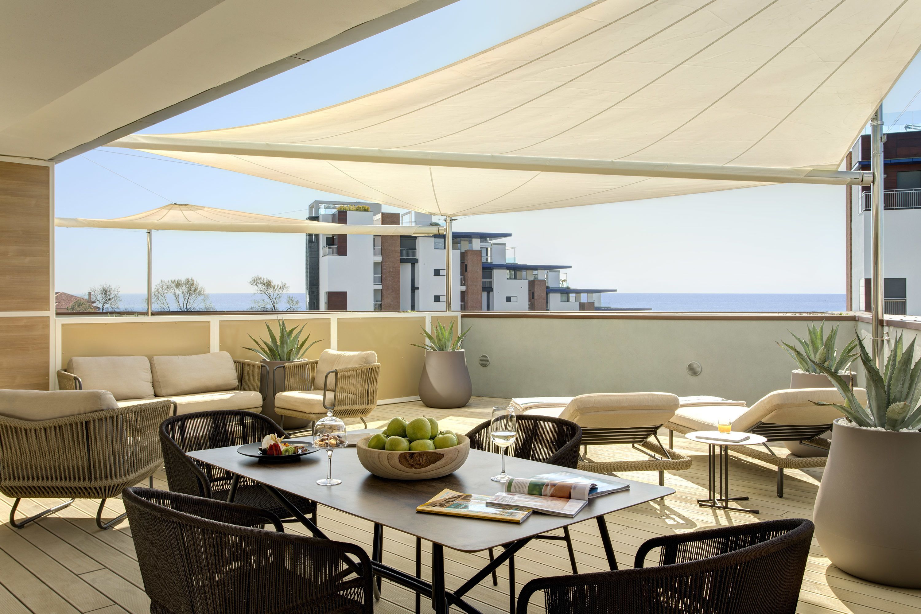 Una terraza en la azotea con mobiliario exterior, una mesa de comedor y plantas en macetas.