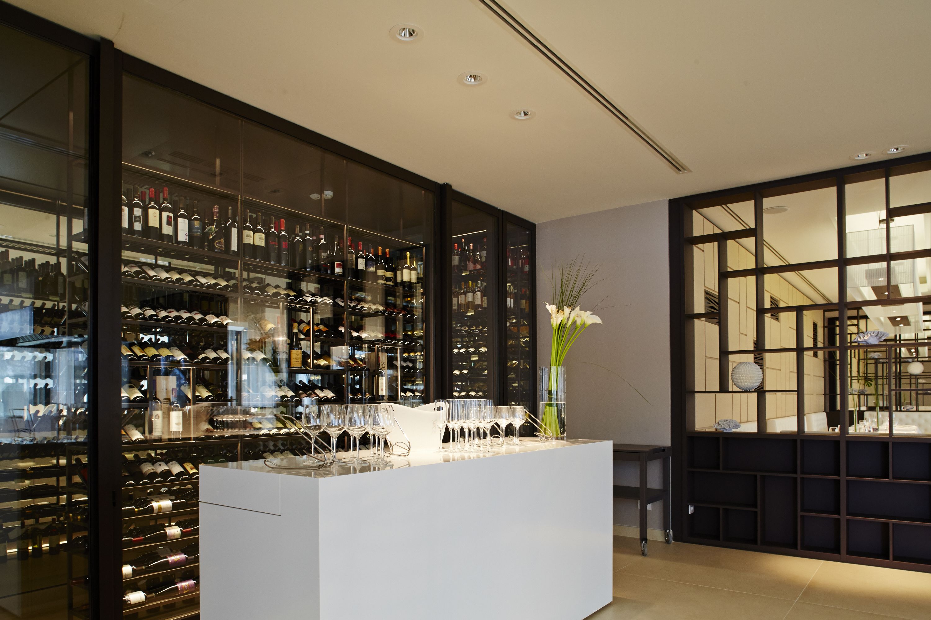 A wine cellar with shelves of wine bottles and glasses.
