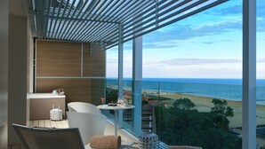 A balcony with a view of the beach and ocean, a seating area with a table, and a small kitchen area. - Almar Lido Jesolo Resort & Spa (Jesolo)
