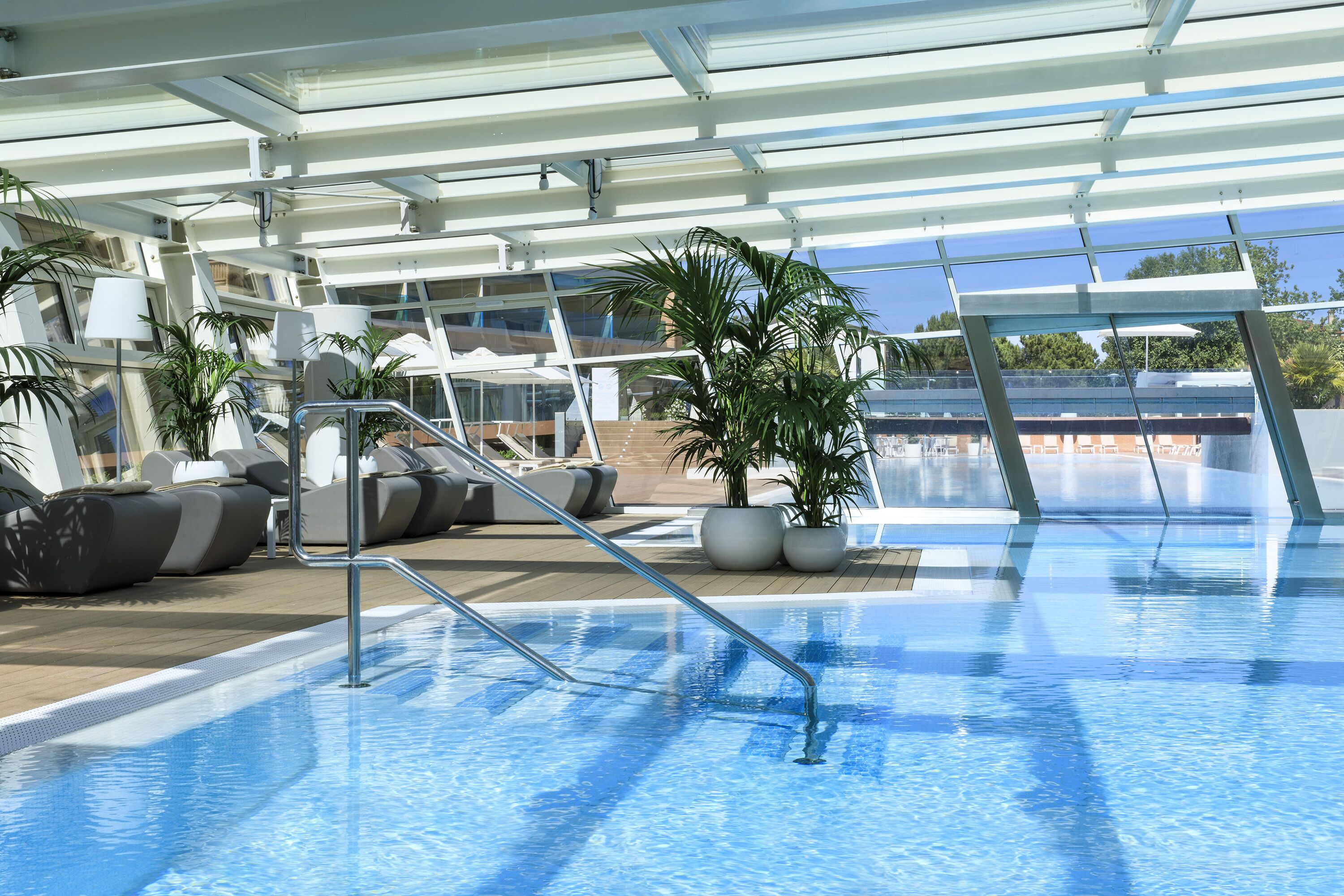 Una piscina en la azotea con sillones de descanso y plantas en macetas.