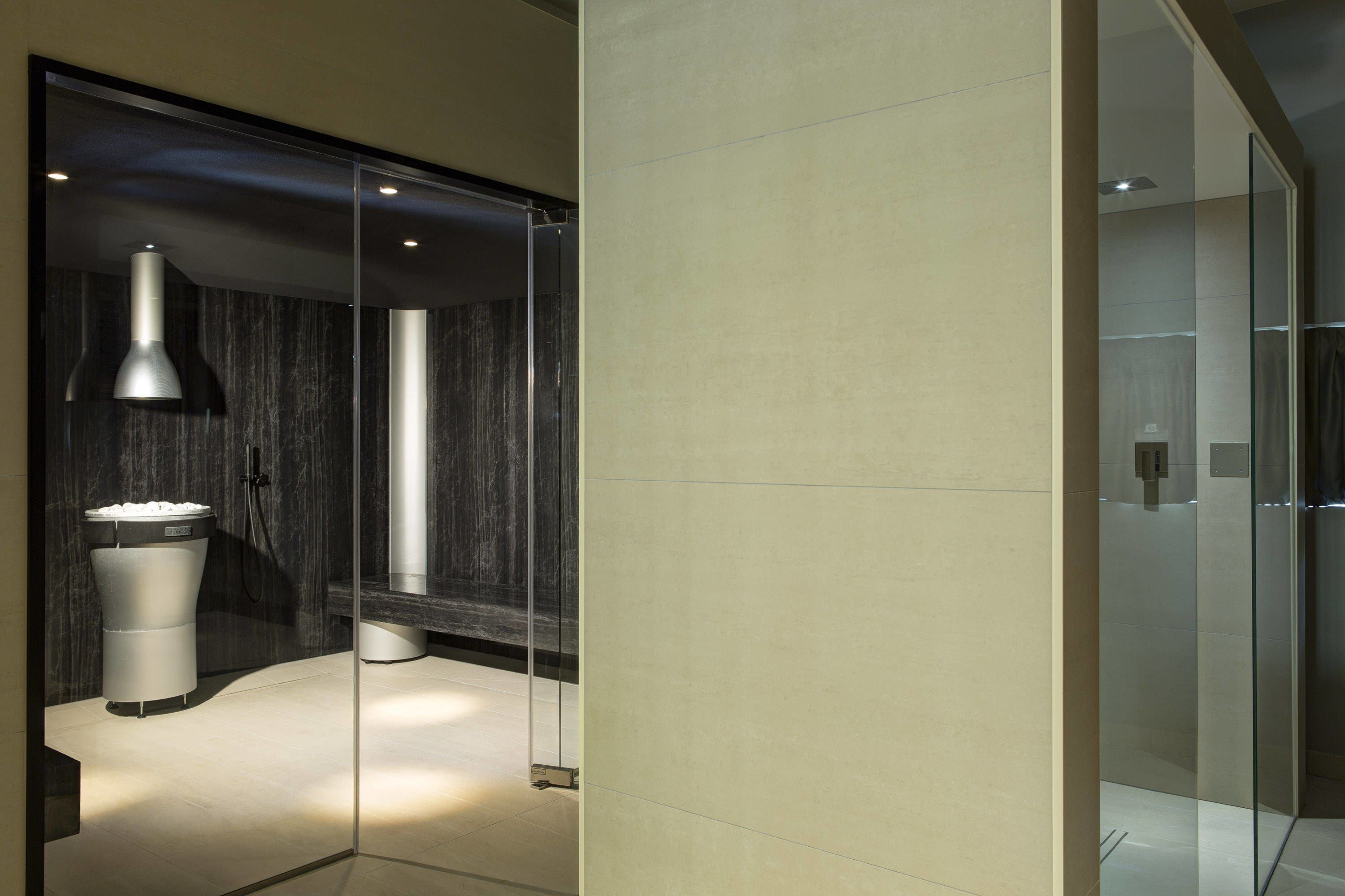 A modern bathroom with a glass shower enclosure, a white pedestal sink, and a sleek pendant light.