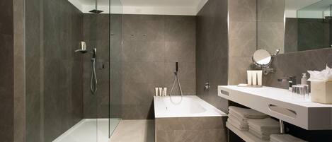 A modern bathroom with a glass-enclosed shower, a freestanding bathtub, and a vanity with a mirror and towel rack.